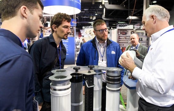 Exhibitor with a product in hand talking to a group of people