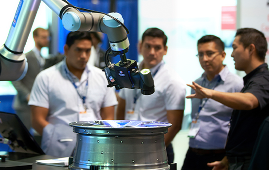 Exhibitor giving a robot demo to three attendees 